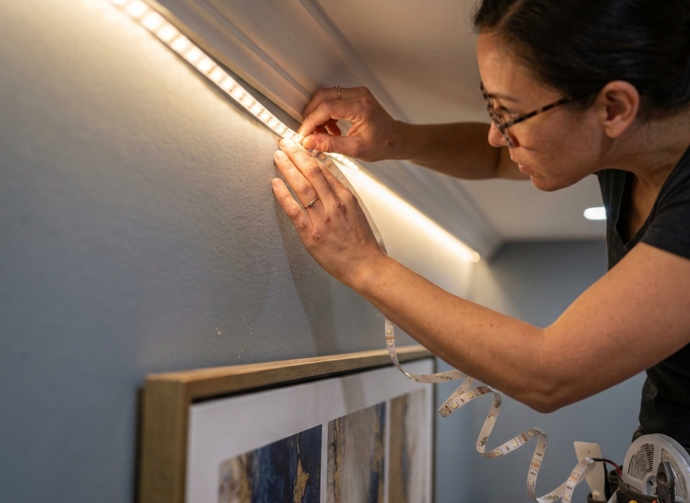 Kobieta montująca taśma LED w sypialni bez uszkadzania ściany