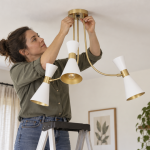 Mujer colocando una lampara de techo en su salón